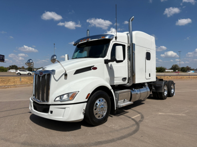 Peterbilt 579 truck in white, side view showing sleeper cab, chrome exhaust stacks, front grille, and dual rear axles.