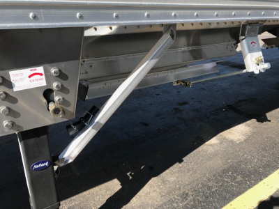 Trailer side view of a 2026 Timpte Super Hopper showing support legs, metal framing, and a Hallite/Holland access label.