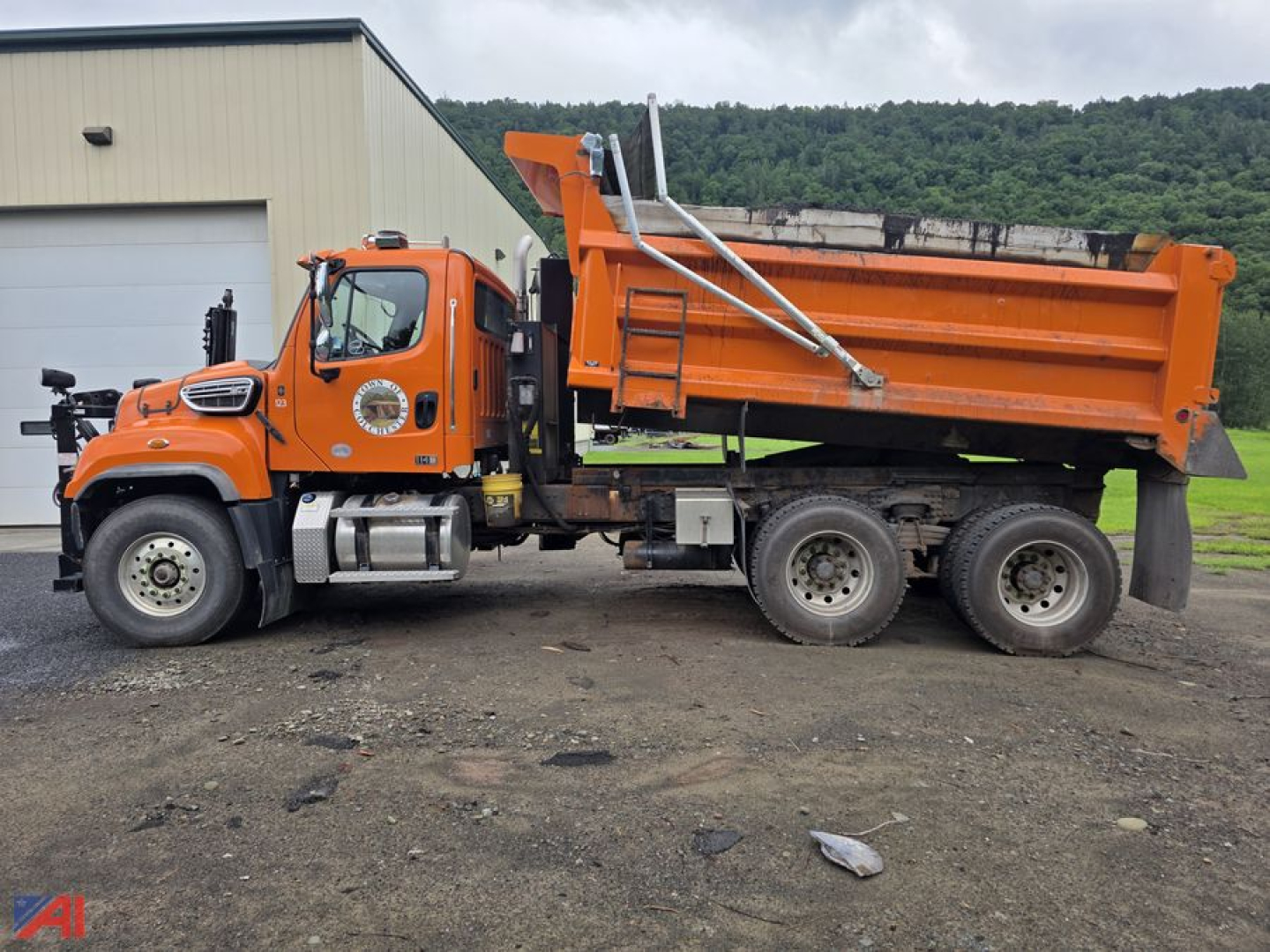 Orange Freightliner 114SD dump truck in-service showing side view with dump bed raised, dual rear axles, and cab with logo.
