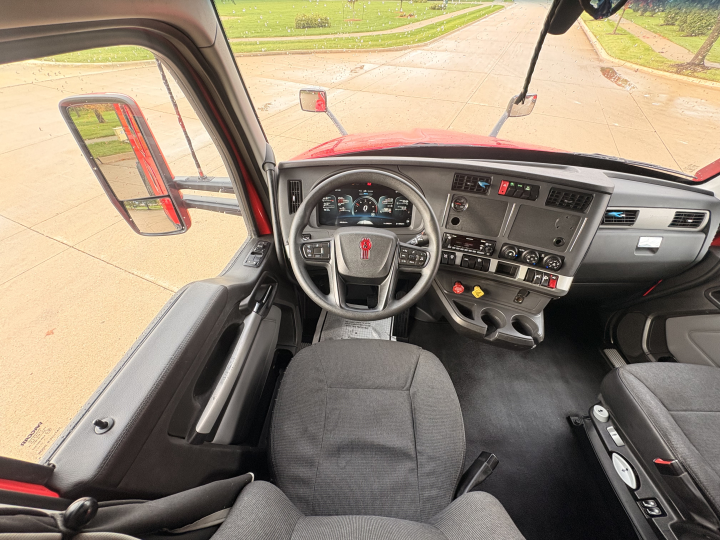 Kenworth T680 interior view from driver seat showing steering wheel, dashboard, and controls.