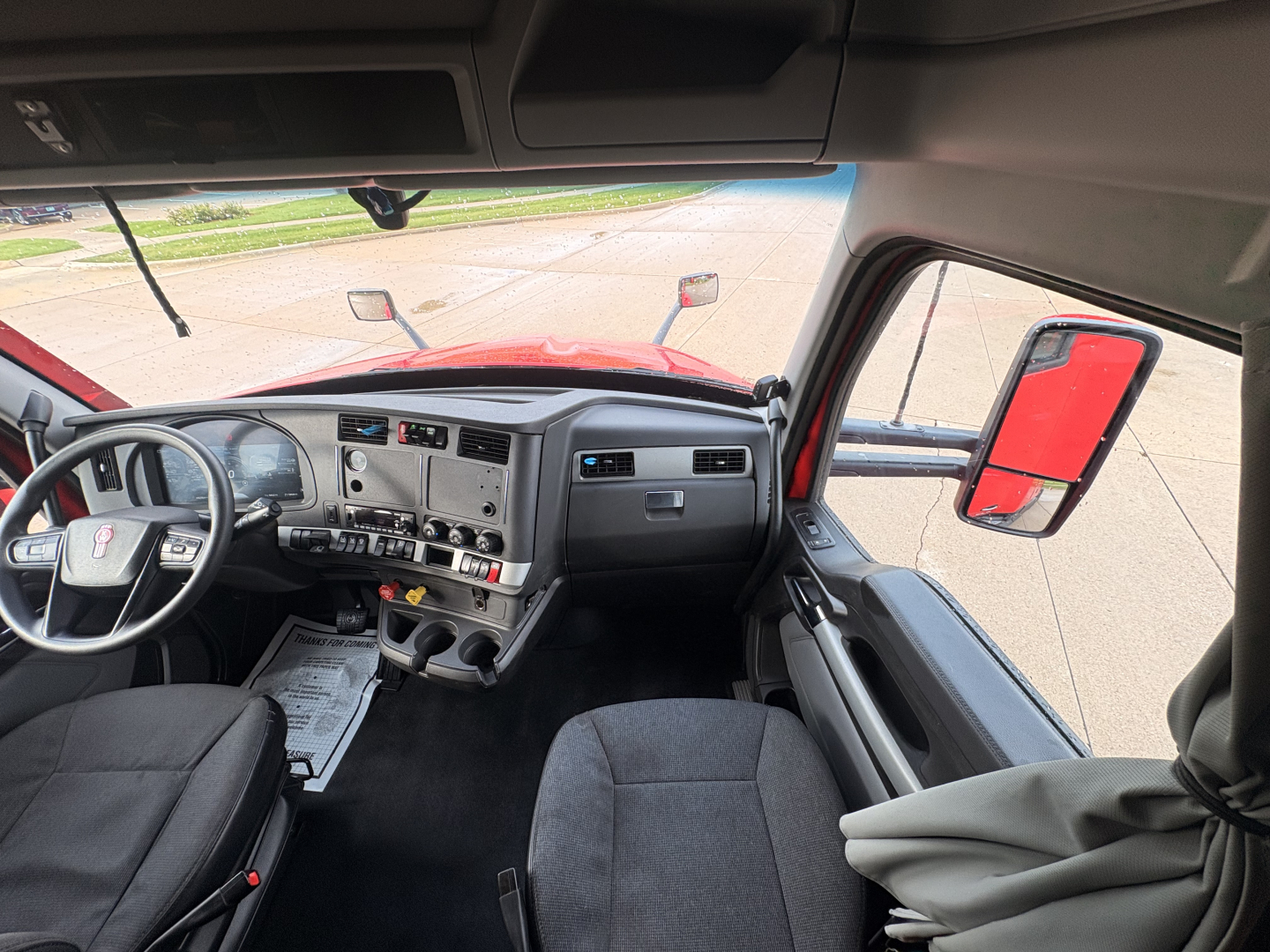 Kenworth T680 truck interior showing steering wheel, dashboard, and front seats.