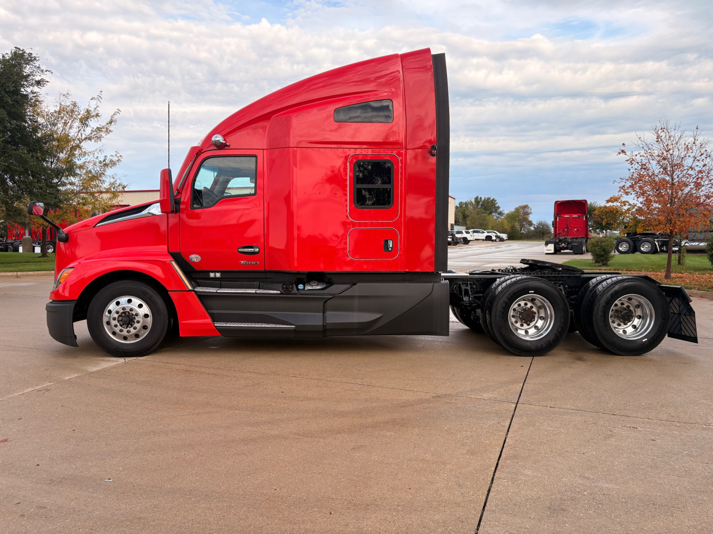 Kenworth T680 sleeper cab tractor in red, side view showing cab, fuel tanks, and triple rear axles with 6 wheels.