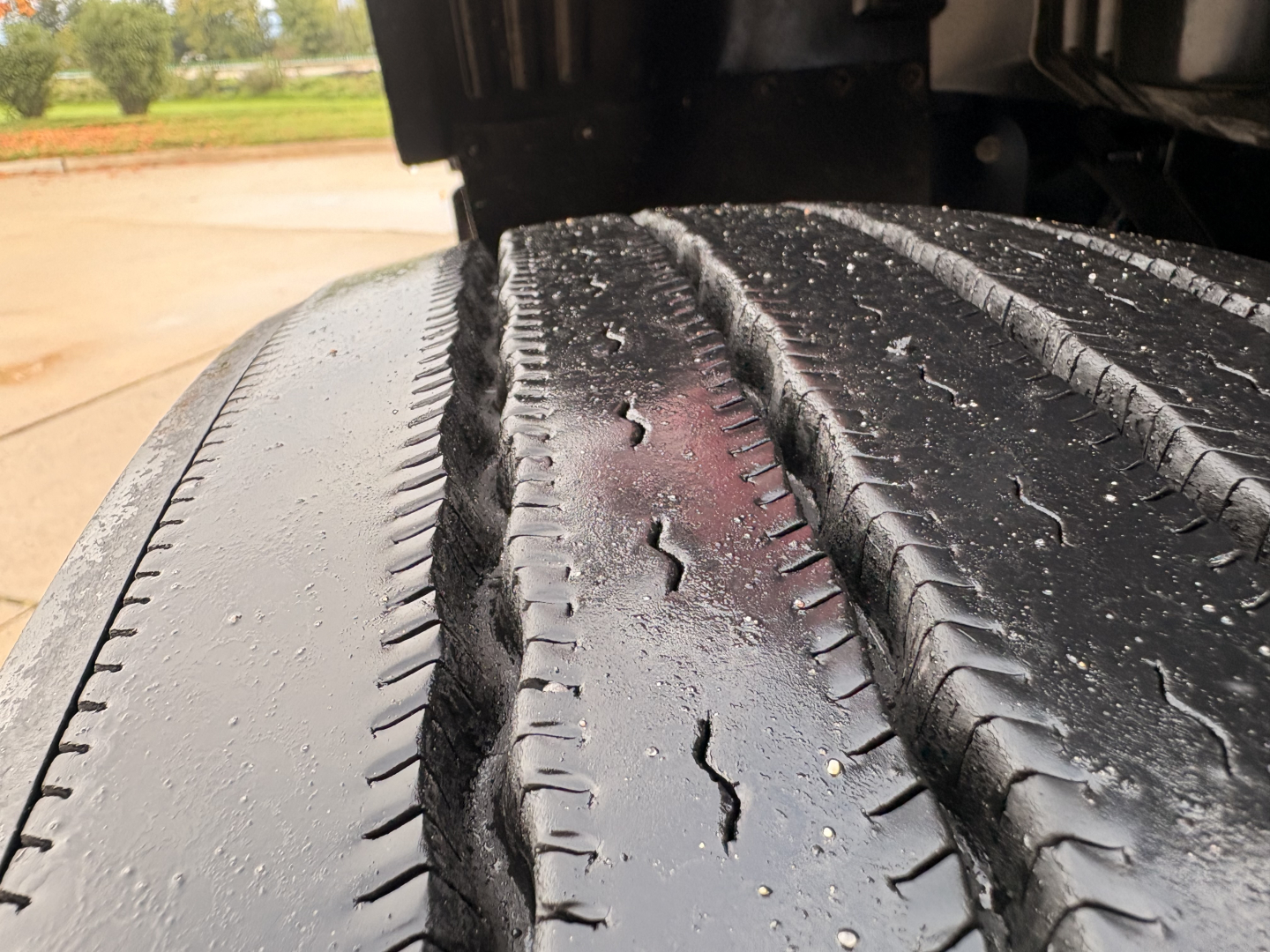 Kenworth T680 wheel tread close-up showing wet dual tires and road grime on the tread grooves.