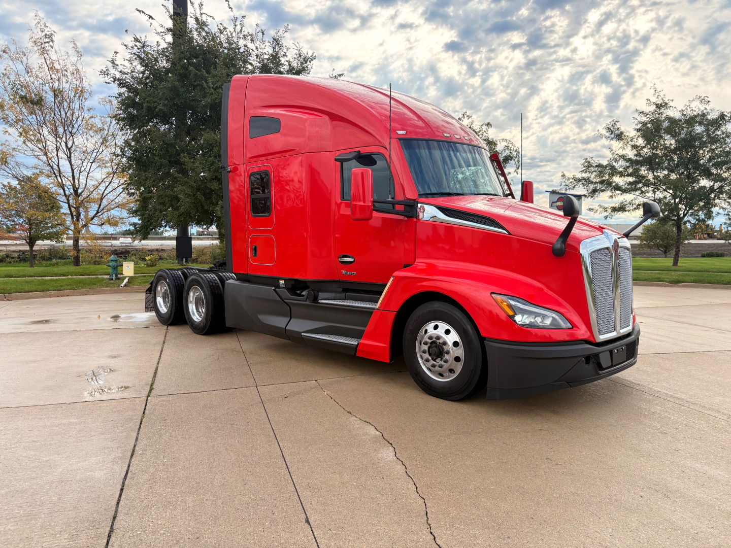 Kenworth T680 tractor in red paint, side view showing sleeper cab, front grille, and wheels.