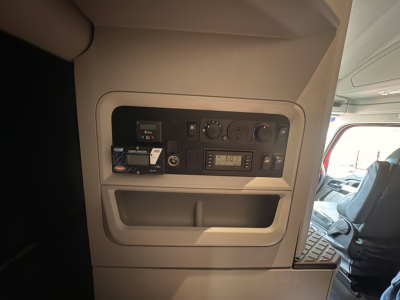 Kenworth T680 cab interior panel showing control switches, displays, and storage pocket near driver seat.
