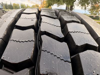 Tire tread close-up on Kenworth truck with muddy, textured rubber and visible seams.