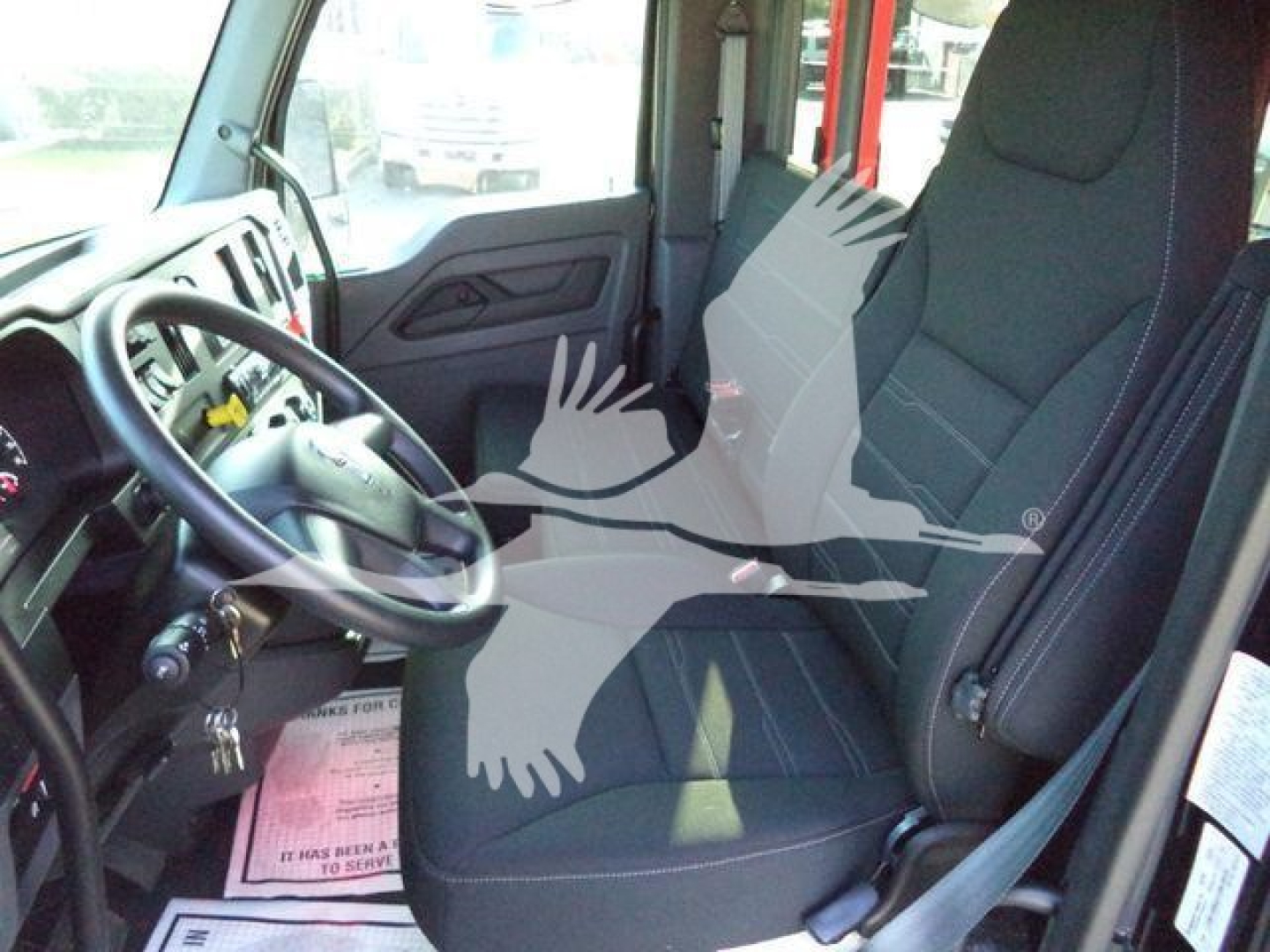 Truck cabin interior of a 2025 Kenworth T280 showing driver seat, steering wheel, and front passenger seat with visible controls and door panel.
