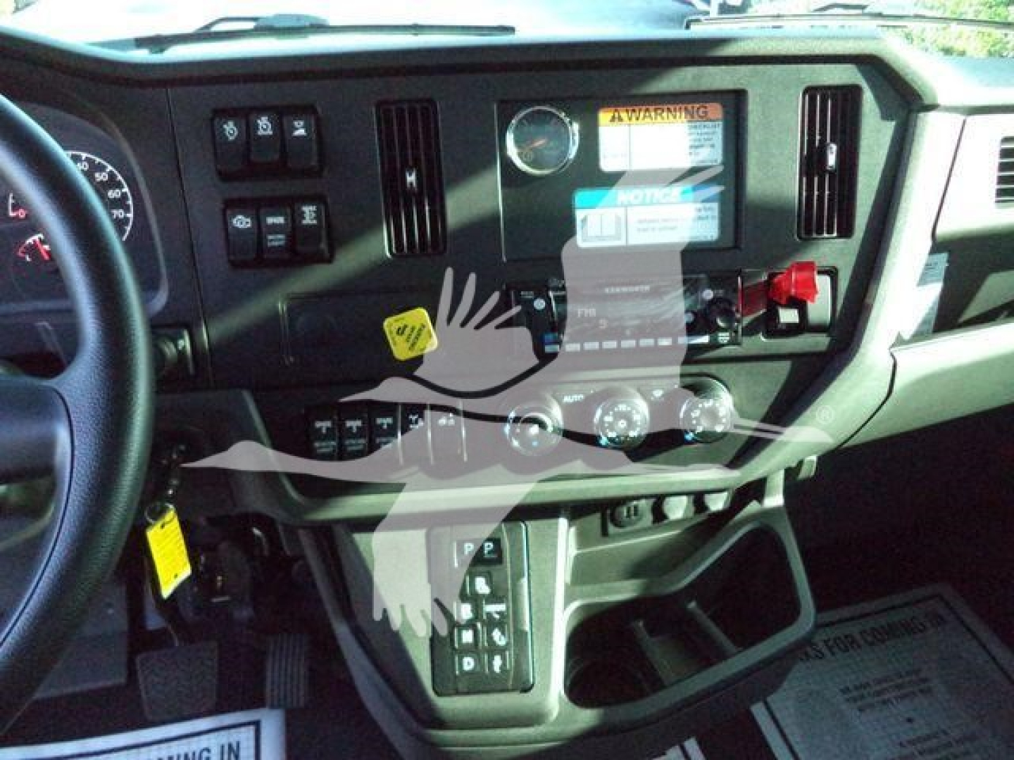 Dashboard of a 2025 Kenworth T280 truck showing steering wheel left, instrument cluster, center console with control switches, gear selector, and warning labels.