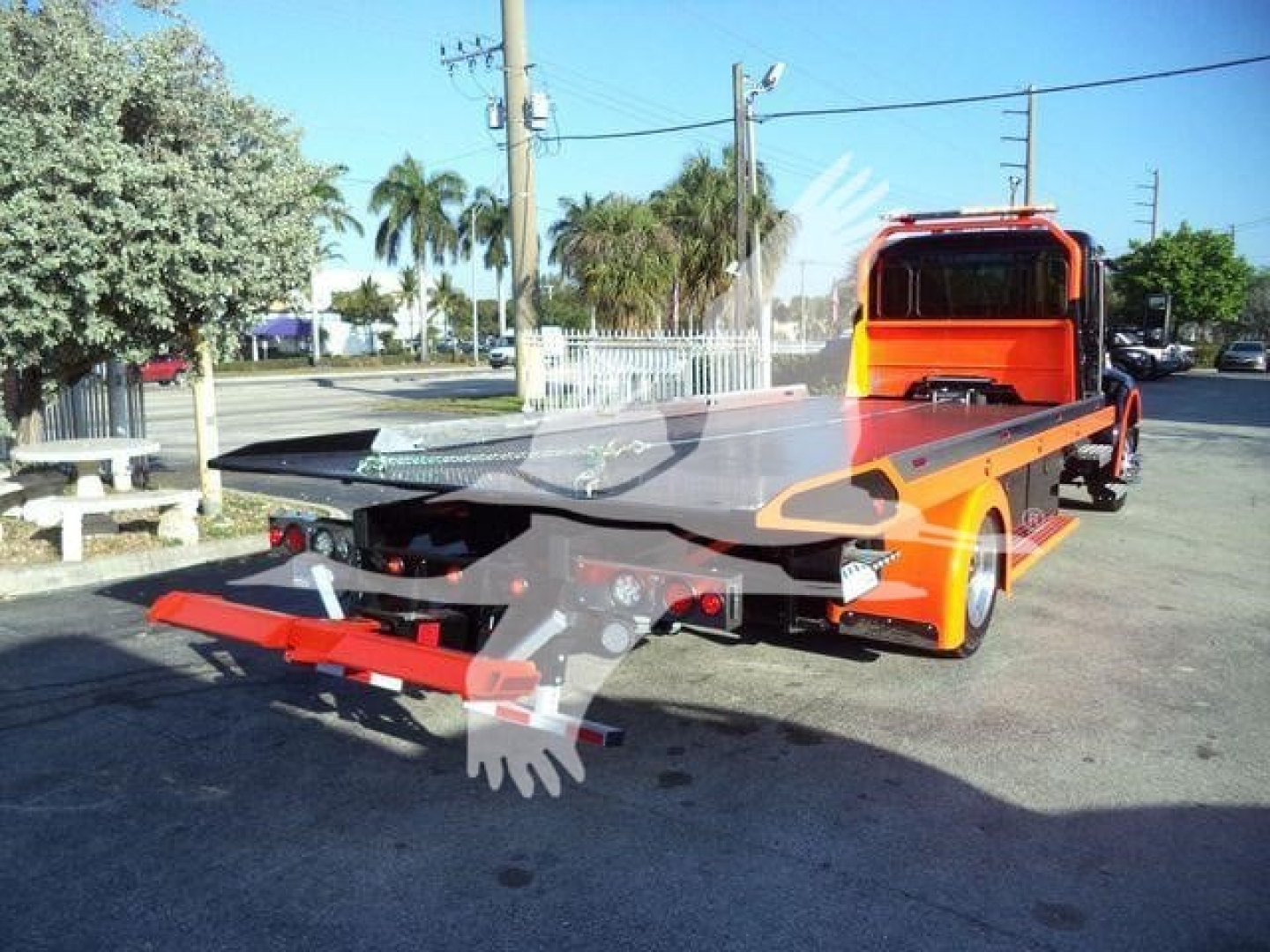 Kenworth T280 rollback tow truck flatbed with orange cab and loading bed visible, side view showing rear ramp and hydraulic system