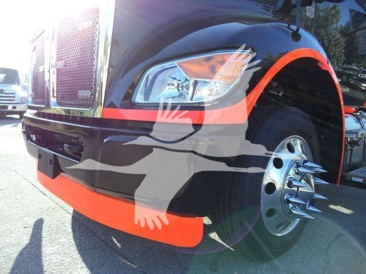 Kenworth T280 front-left view showing chrome grille, headlight, black paint with orange accents, and dual-wheel front hub with polished spokes.