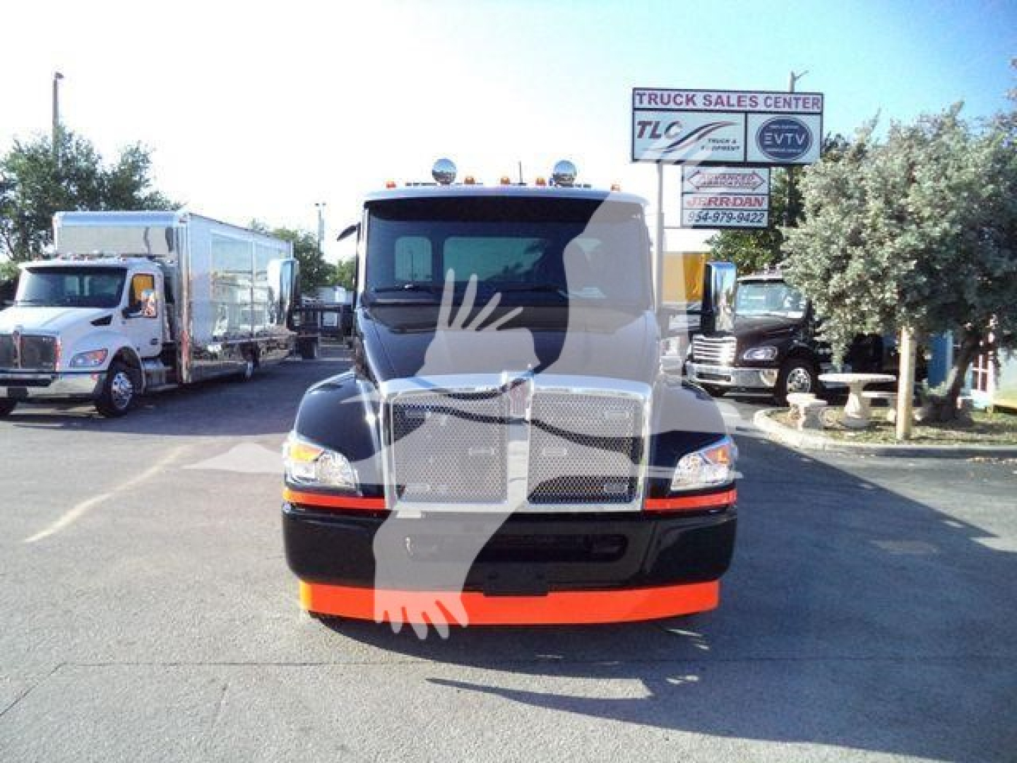Front view of a black 2025 Kenworth T280 truck with orange bumper guard, daytime dealership lot in background.