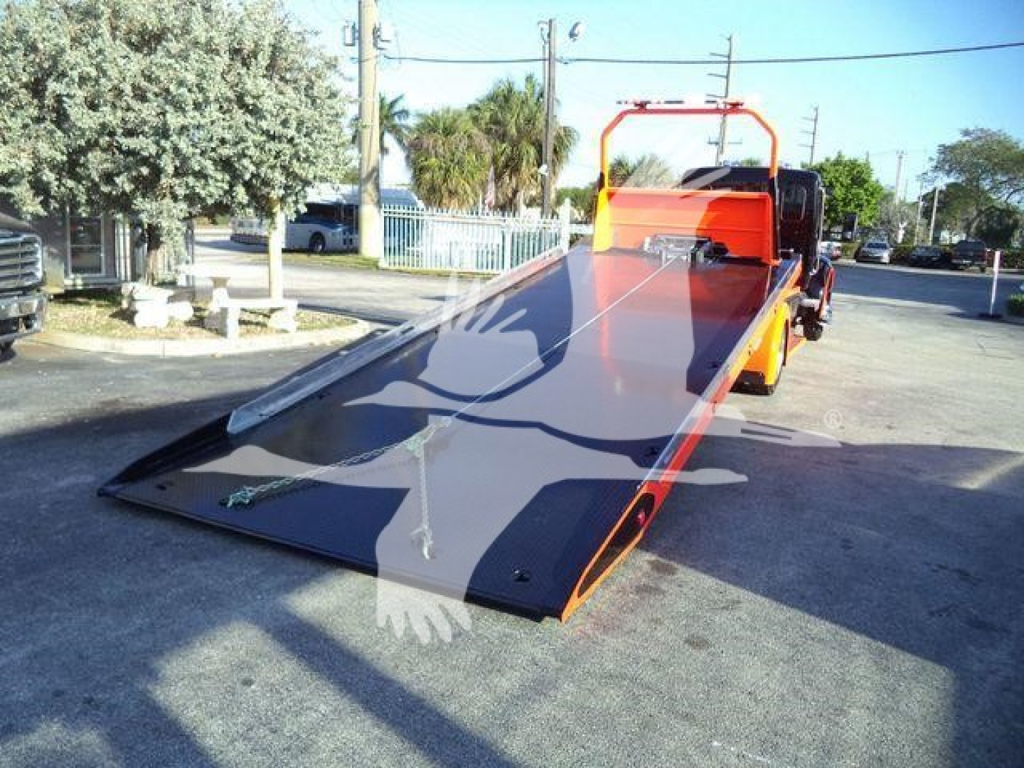 Kenworth T280 rollback bed truck with a lowered flatbed/rollback ramp, orange cab, and black ramp sections visible.