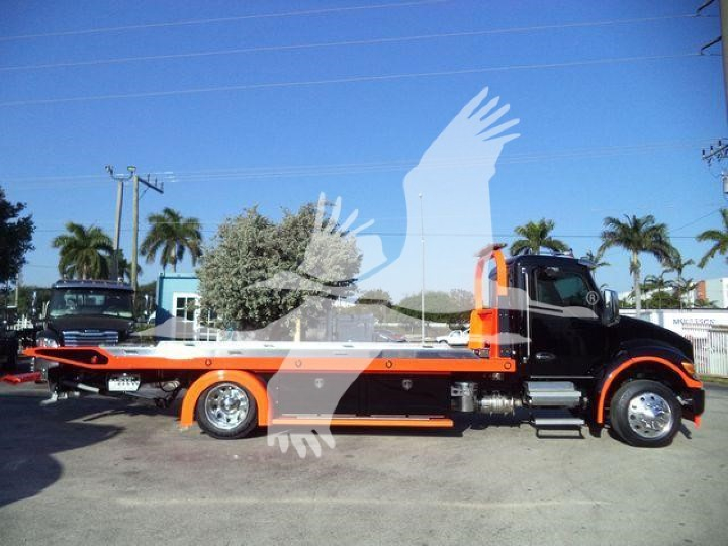 Kenworth T280 rollback truck side view showing orange and black color scheme with flatbed and hydraulic ramp.