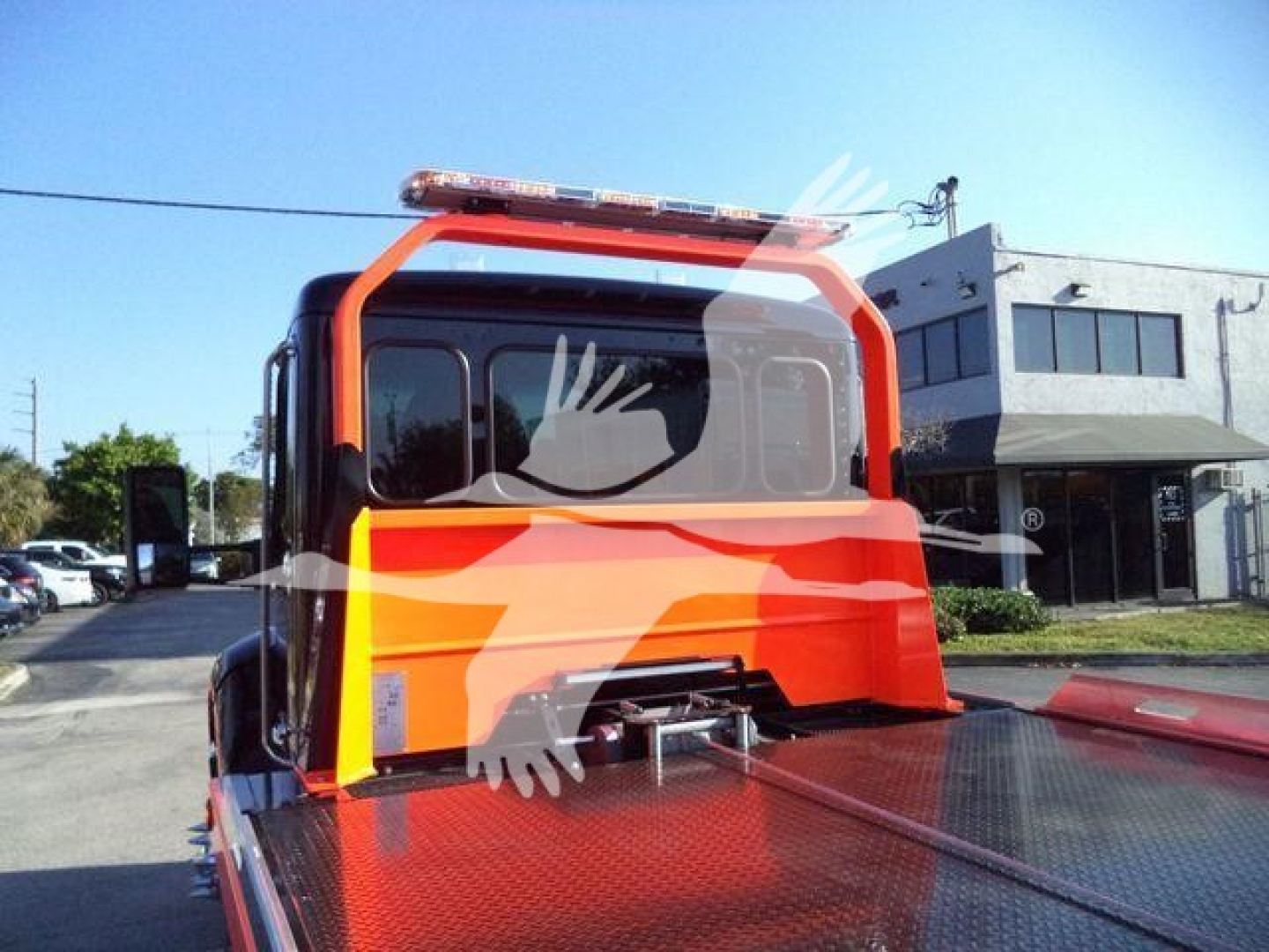 Kenworth T280 rollback truck cab rear view showing diamond plate bed and orange rollover protection frame with light bar on top.