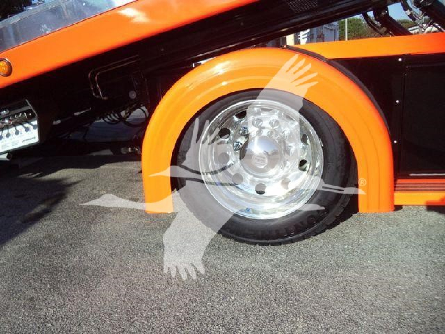 Kenworth T280 side view showing orange fender and wheel with chrome hubcap and black body panel.