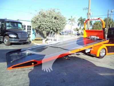 Tow truck rollback bed on a 2025 Kenworth T280 with a low, flatbed and orange safety rails, showing a black ramp and loading platform.