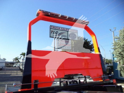 Kenworth T280 rollback truck rear view with bright red back panel and black lower section; visibility shows a sign in the rear window with Truck Sales Center TLC lettering.