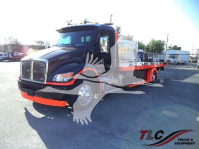 Kenworth T-M series truck with a flatbed rollback body, black cab and orange lower bumper. Side view shows extended flatbed with wheel ramps. TLG logo watermark across image.