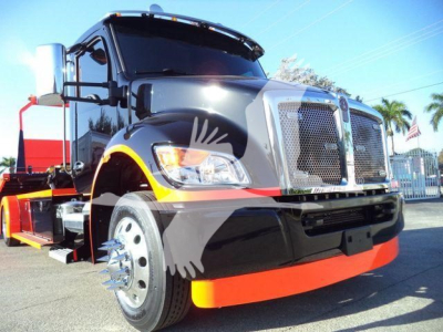 Kenworth T280 front-left view showing large chrome grille, black body with orange bumper lip, and side mirrors. Headlights visible with amber indicator, wheel with chrome hub, and drop-guard fascia.