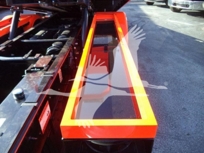 Kenworth T280 rollback truck bed with bright orange metal framework and reflective edges, storage area and hydraulic components visible.