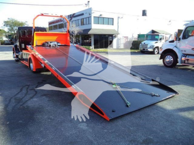 Kenworth T280 rollback truck with hydraulic flatbed incline ramp in a dealership lot.