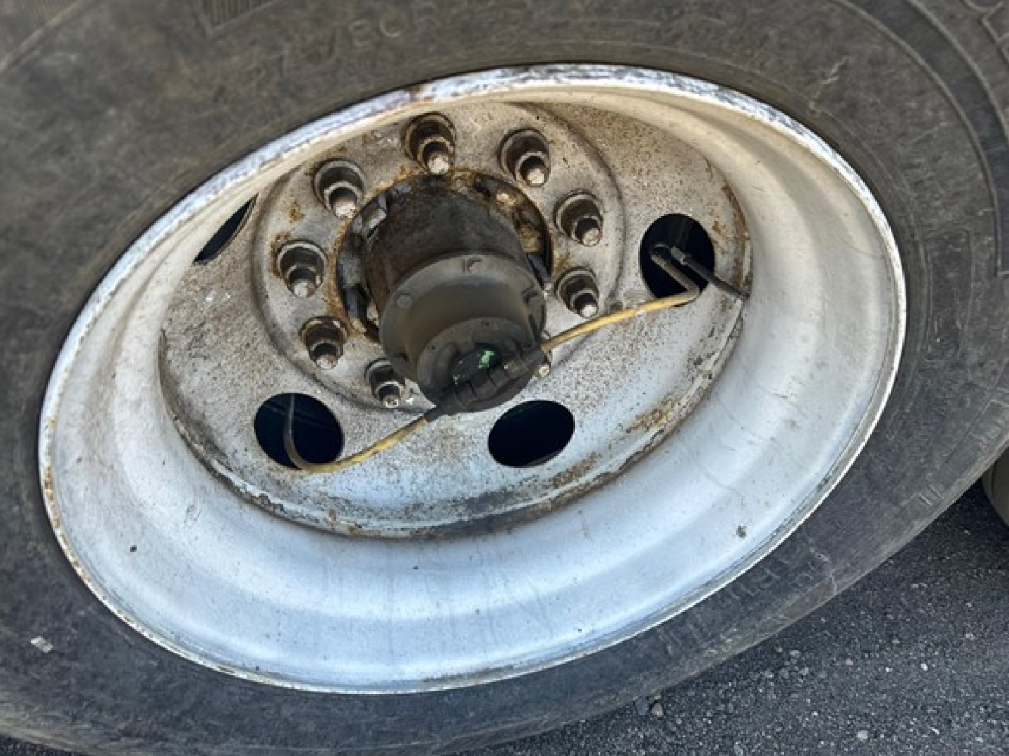 Hyundai air ride dry van wheel hub showing rusted lug nuts and a black hub, with a thin wire loop across the rim.