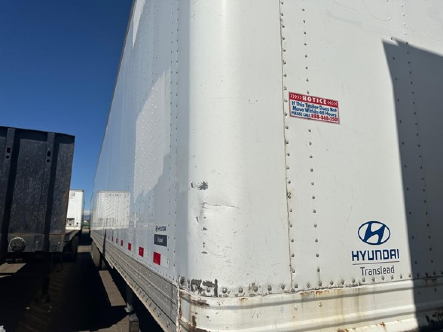 Hyundai Translead trailer side with warning sticker and Hyundai logo. Visible text includes HYUNDAI Translead, notice sticker, and riveted seam details.