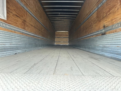Trailer interior displaying empty cargo area with wooden walls and metal ribs, cargo floor seen extending to back, no text visible