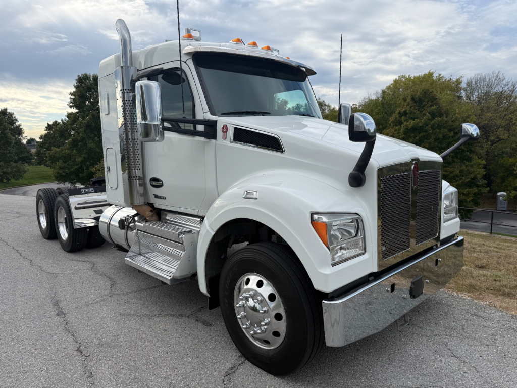 Kenworth T880S conventional sleeper truck in white, front-left view, showing chrome grille, diesel fuel tanks, steps, mirrors, and dual rear axles.