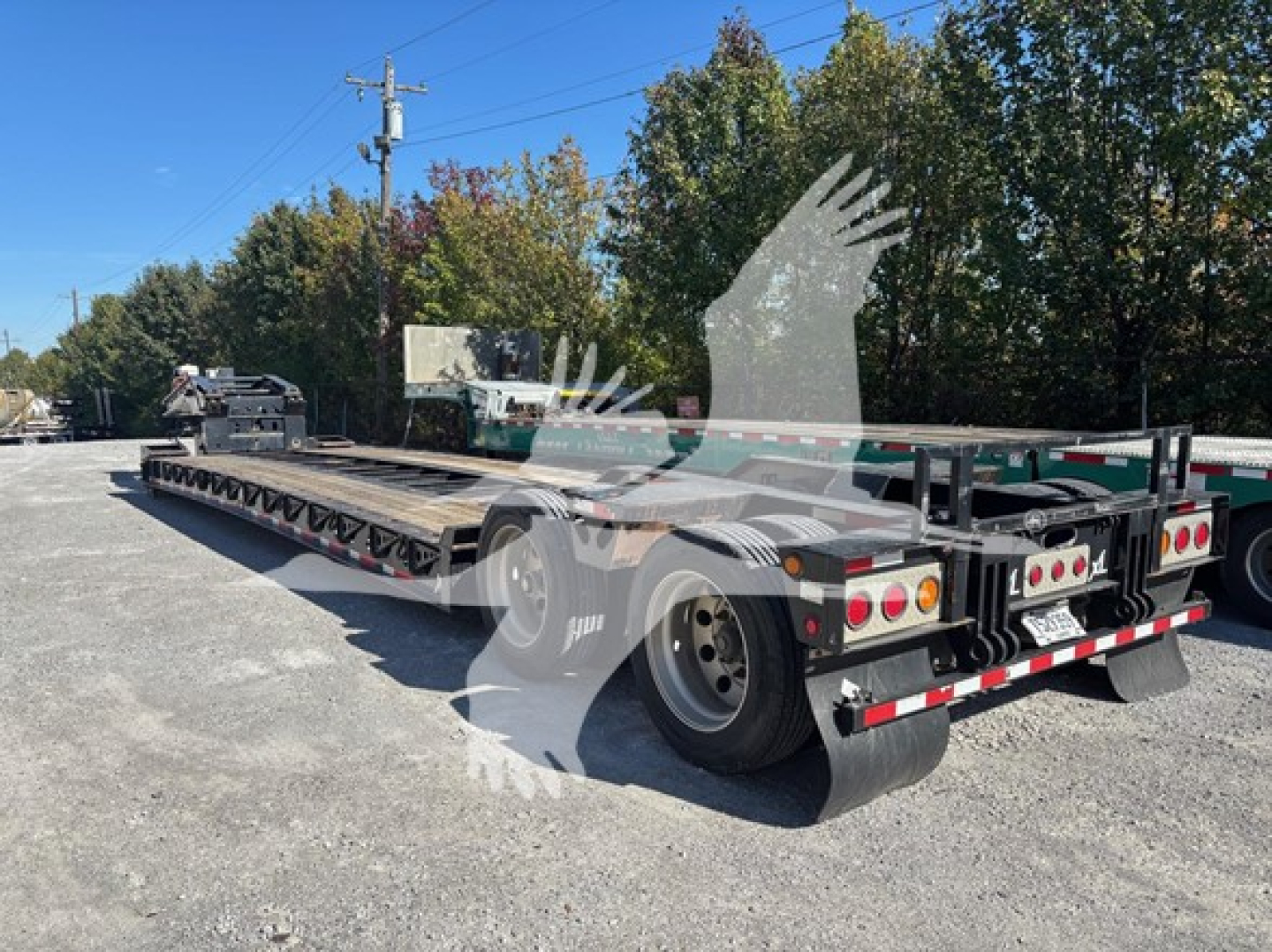 XL Specialized XL80HDG lowboy trailer showing rear and side, aluminum deck, tandem axles, rear lights, and reflective markings.
