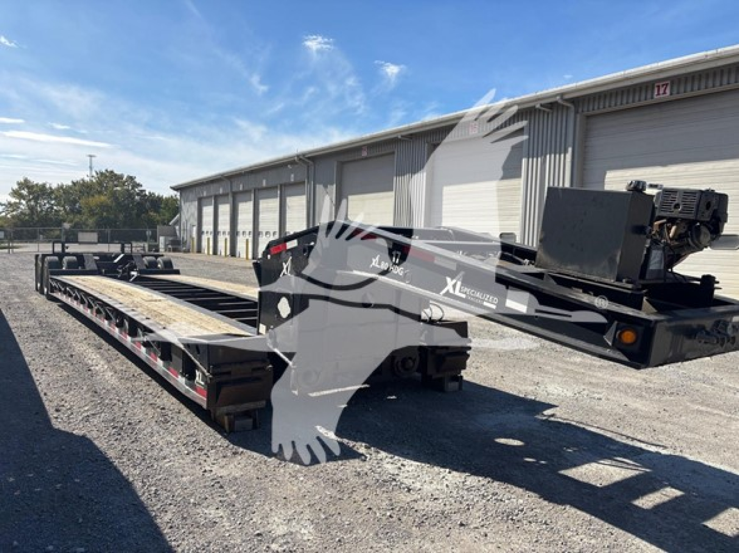 Flatbed trailer in a yard showing XL Specialized XL80HDG branding on the side with a mounted gooseneck/tractor hitch area.