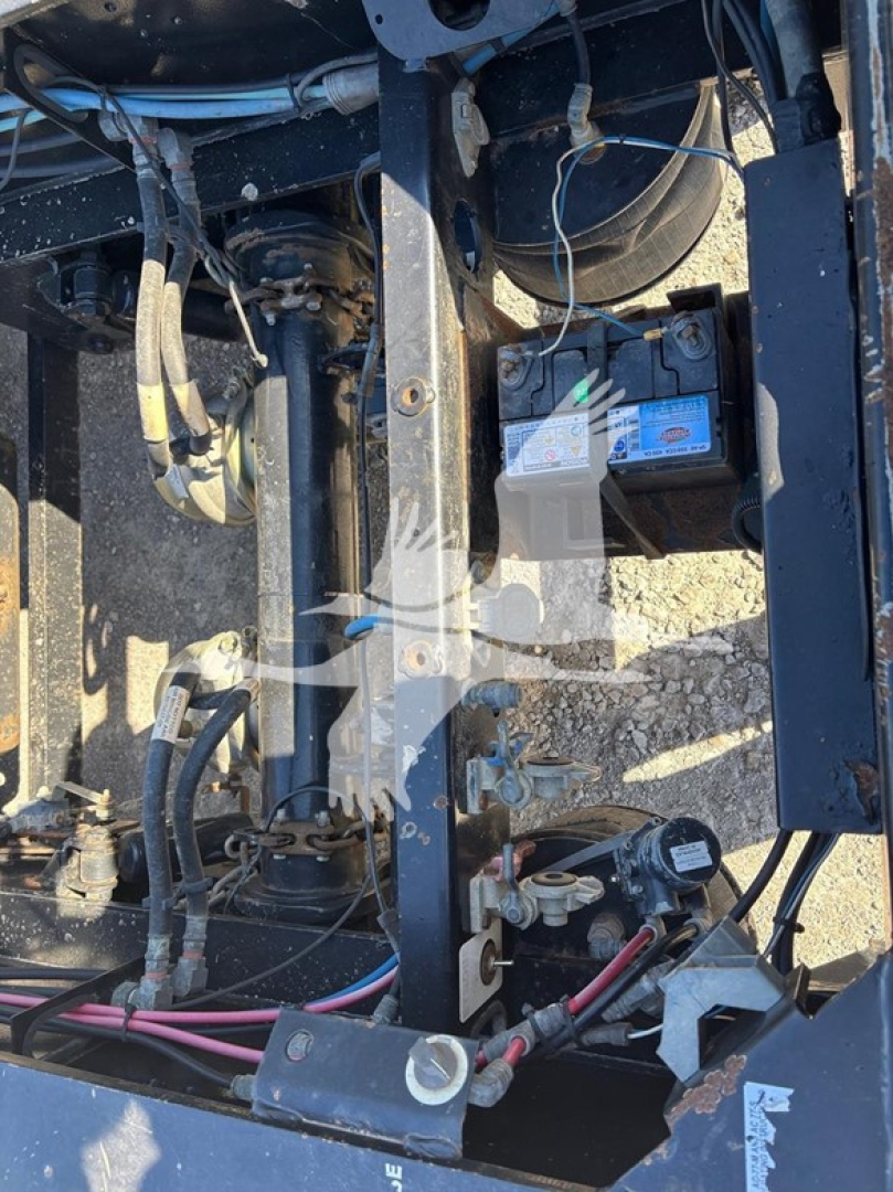 Trailer frame and battery area showing wiring, hydraulic lines, and control components on a XL Specialized XL80HDG lowboy trailer (engine bay area visible).