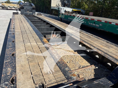 Trailer deck showing wooden planks and metal rails on XL Specialized XL80HDG lowboy trailer with debris and shadows.