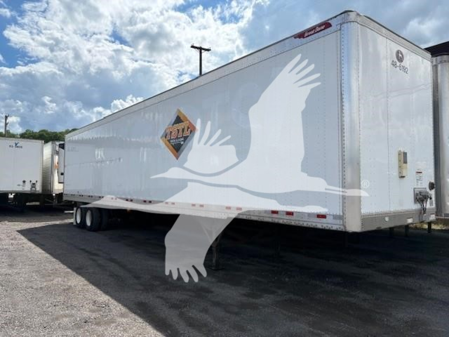 Great Dane dry van trailer with white exterior featuring a large flying bird decal, two rear doors, and a warning diamond placard on the side.