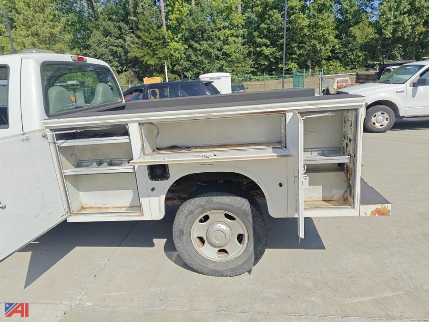 Side view of a 2006 Ford F350 utility truck with open utility body compartments and a single rear wheel visible.