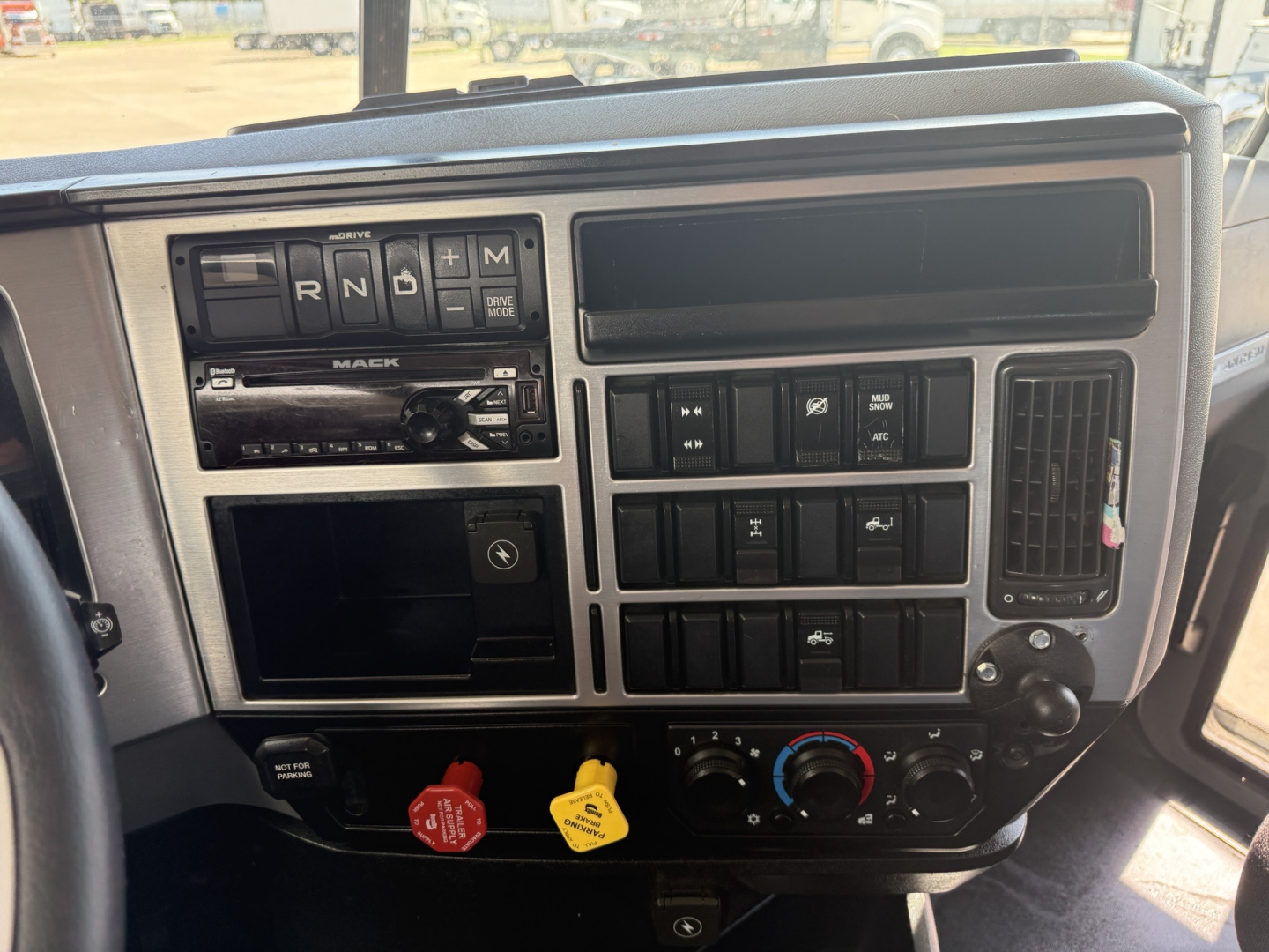 Dashboard of a 2020 Mack AN64T daycab showing gear selector, multiple switches, and climate controls.