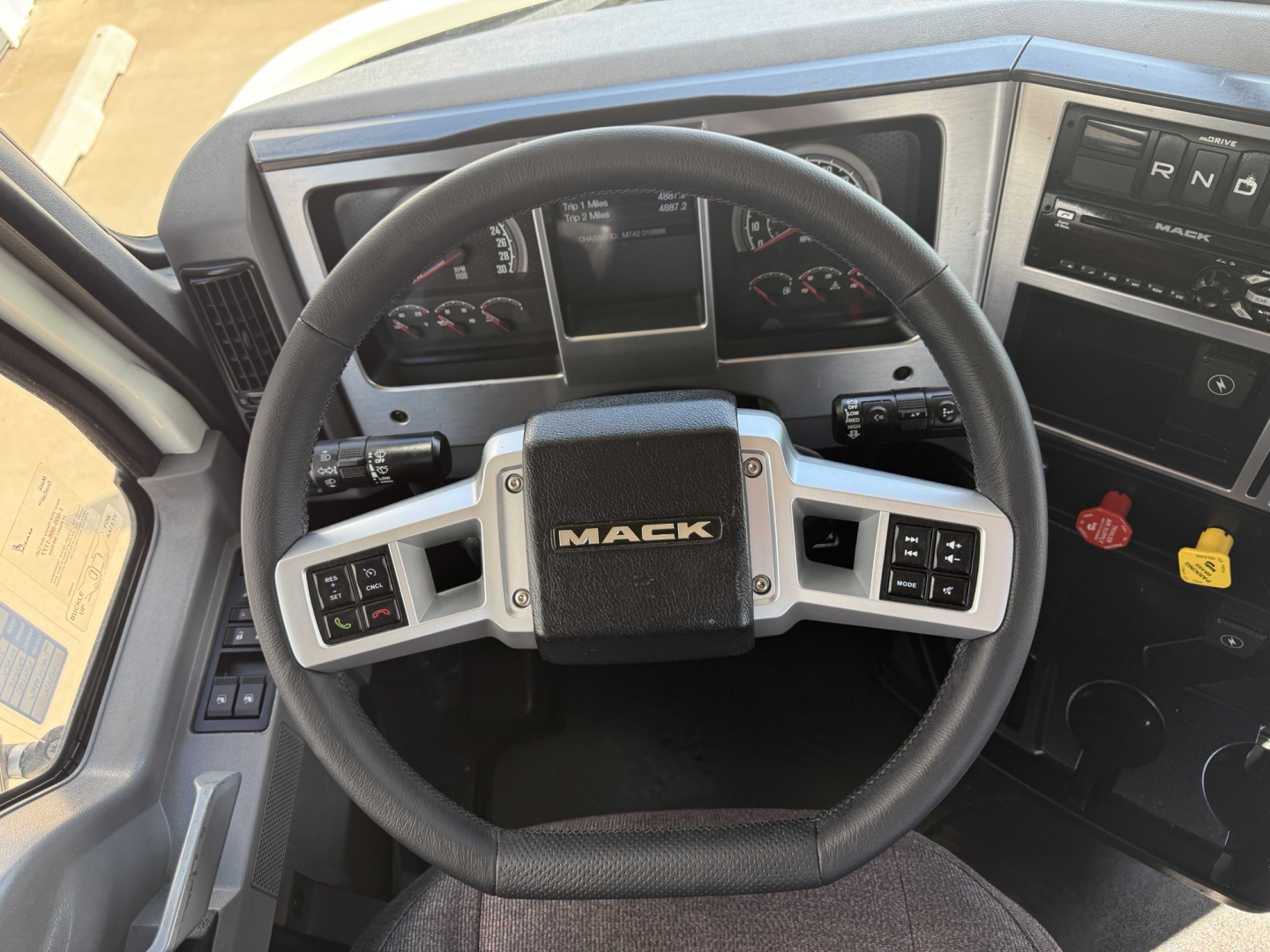 Mack AN64T truck interior steering wheel with dashboard gauges and controls visible.