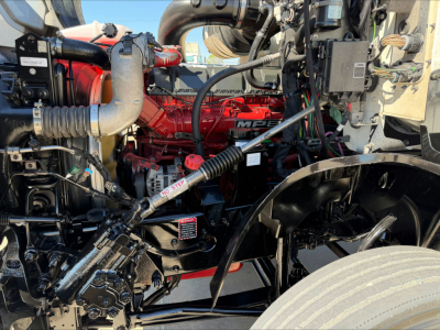 Engine bay of a 2020 Mack AN64T conventional daycab showing red engine block and surrounding hoses, hoses, and components.