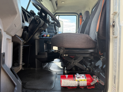 Cab interior of a 2020 Mack AN64T daycab showing driver seat and dashboard with a red fire extinguisher on the floor.