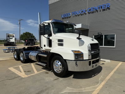 Mack AN64T conventional daycab truck in a lot showing front and side view with chrome bumper and dual rear axles.