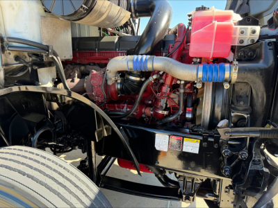 Mack AN64T engine bay showing red engine block, blue silicone hoses, pink coolant reservoir, and black frame.