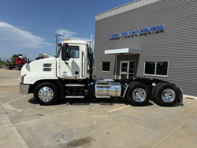 Mack AN64T truck side view showing F-series cab and dual rear axles in front of Used Truck Center building.