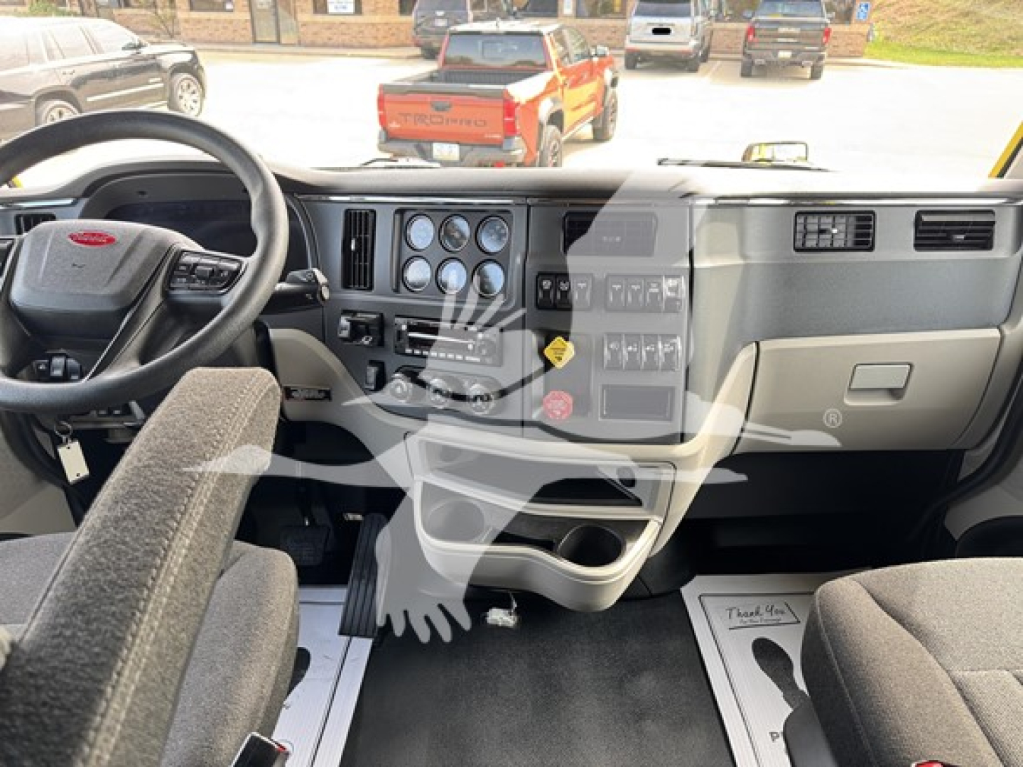 Dashboard view of a Peterbilt truck interior showing steering wheel, instrument cluster, center console, and plastic storage compartments.