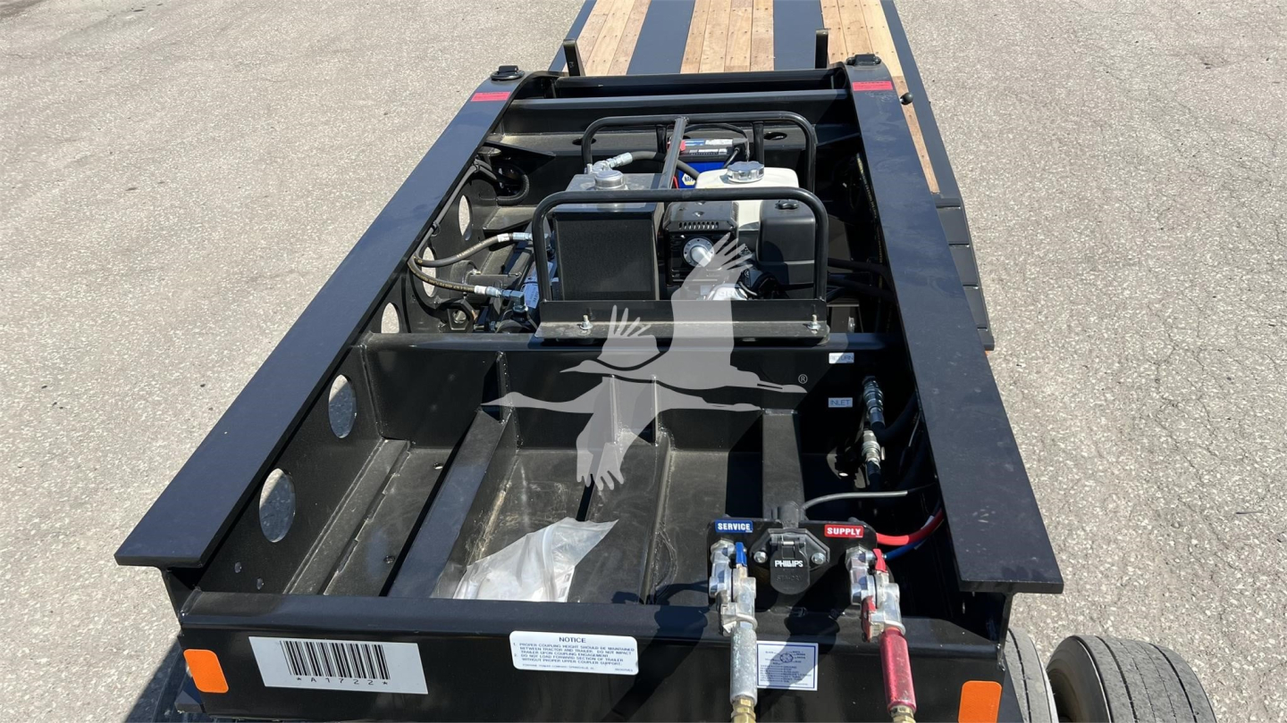 Trailer engine bay and hitch area of a Fontaine Renegade XN20 lowboy trailer showing rear engine housing, battery, hoses, and control levers.