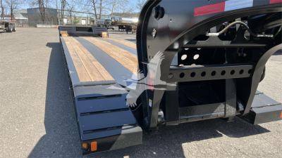 Fontaine Renegade XN20 lowboy trailer showing wooden deck planks and black steel frame near hitch with cutouts and ramps.