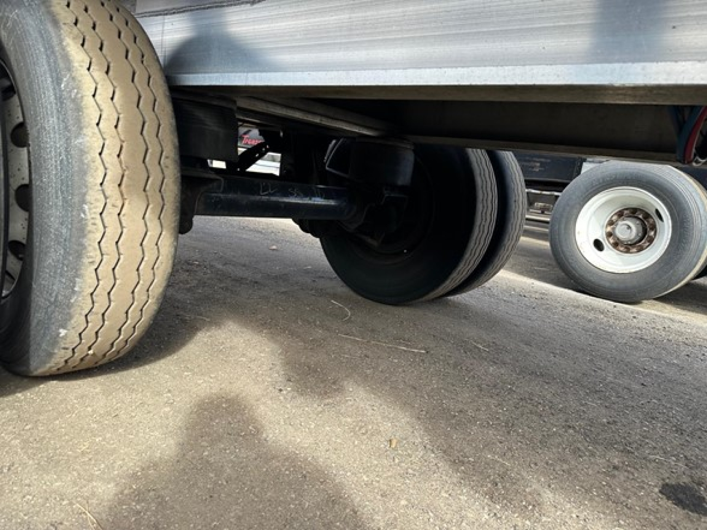 Trailer underside with tandem axle tires and leaf spring suspension showing undercarriage of 2014 Transcraft 53' all-aluminum flatbed.