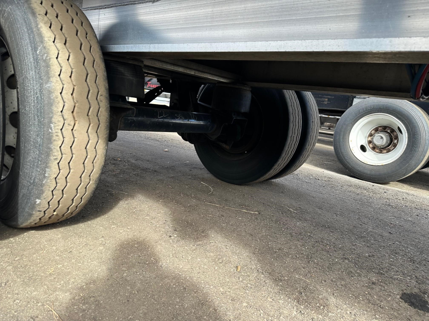 Trailer underside showing dual rear axles and wheel assembly with tires in view.
