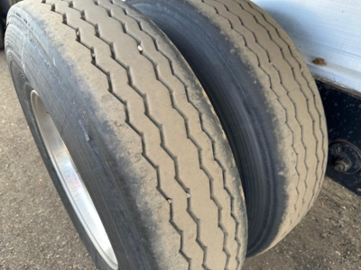 Two truck tires mounted on a flatbed trailer showing tread pattern and sidewall detail.