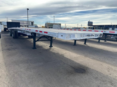 Flatbed trailer with aluminum 53' Transcraft, side rails with reflective tape, landing gear, and support legs visible in a used trailer lot.