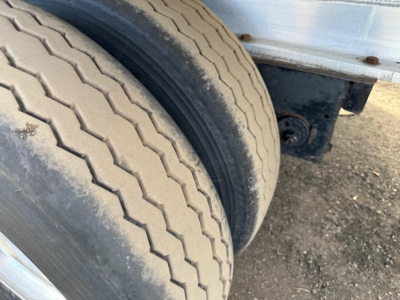 Dual rear wheels on a 2014 Transcraft 53' all-aluminum flatbed trailer showing treaded tires and a portion of the aluminum body.